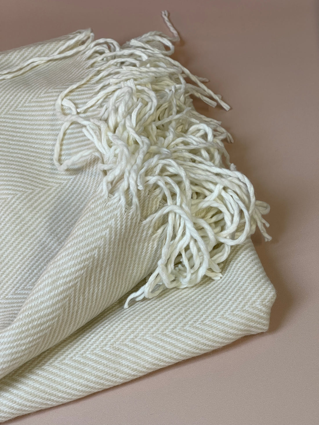 Soft cream throw blanket with textured weave, perfect for cozying up on chilly evenings or adding a touch of warmth to your decor.