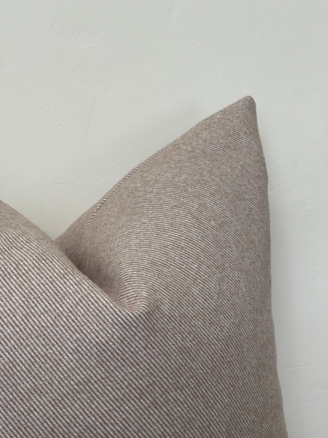 Soft beige wool-effect cushion with feather insert, blending luxury, neutral tones, and timeless aesthetic for elegant home decor.